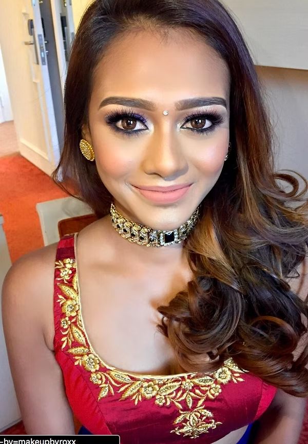 Bridal makeup with gold-embroidered blouse and statement choker, backstage